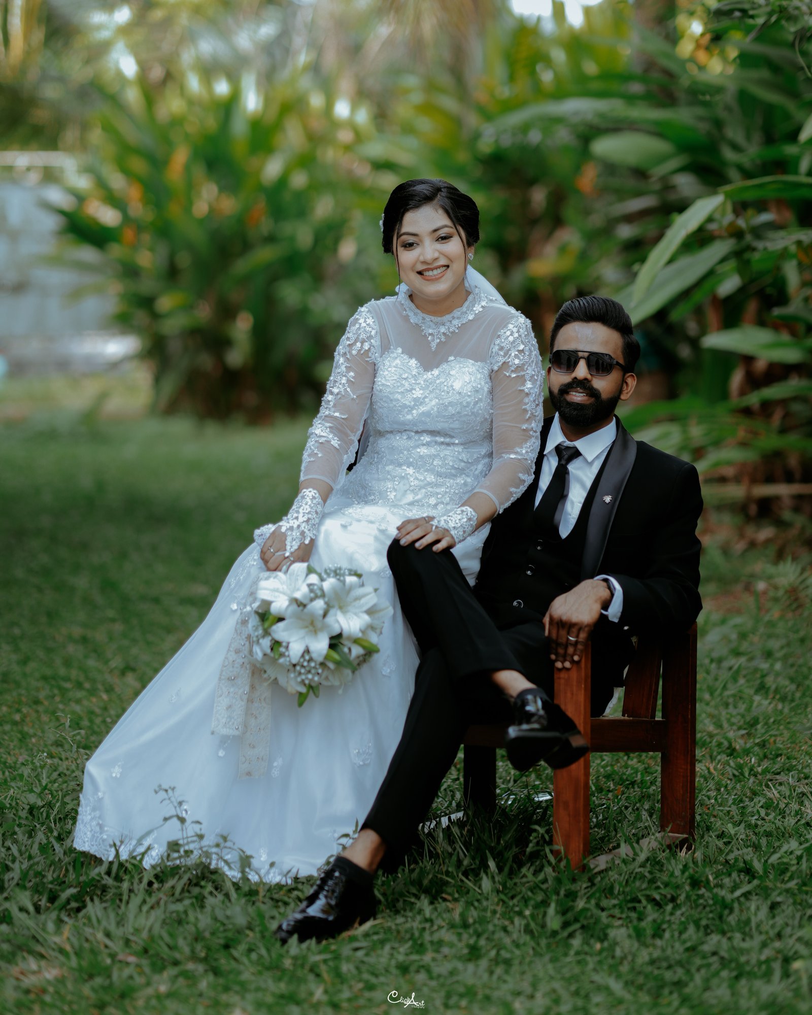 A newlywed couple seated together in a tropical garden