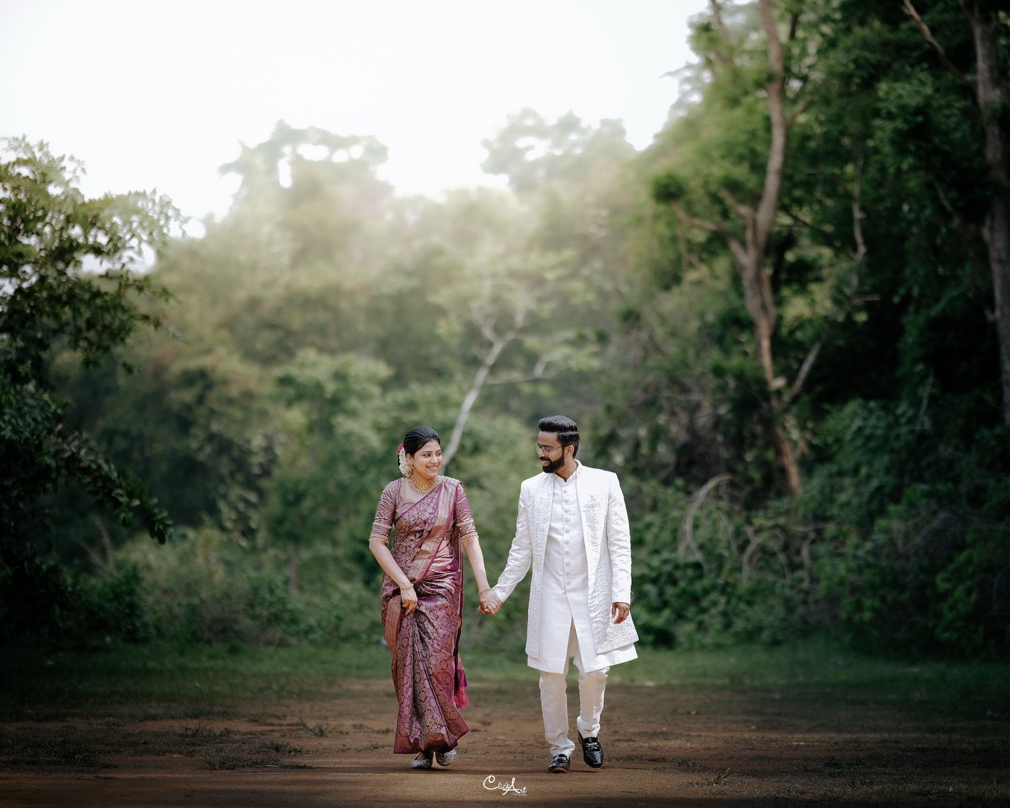 A couple walking hand in hand through a wooded landscape