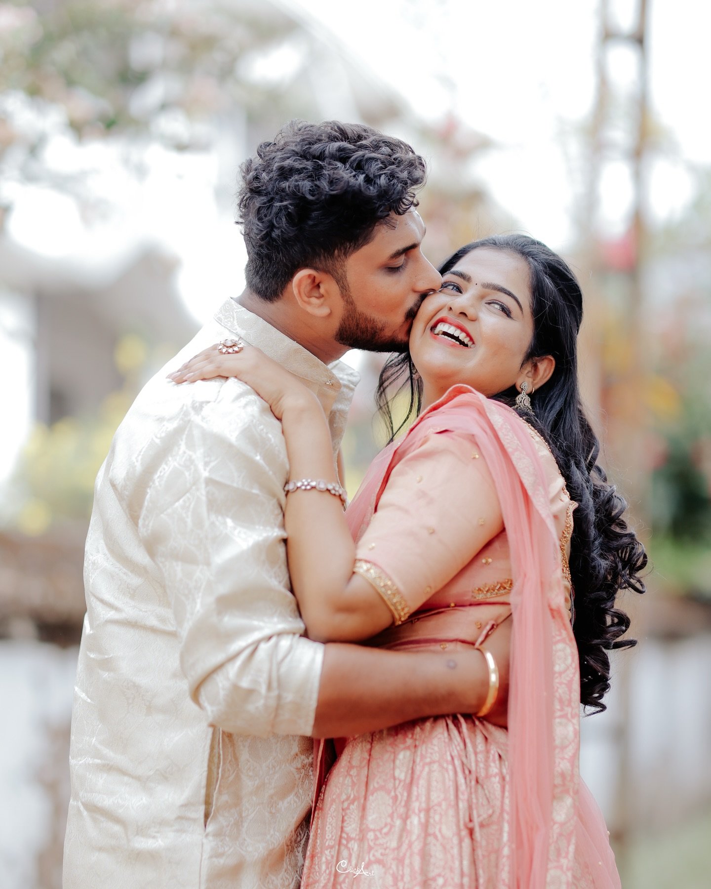 A groom kissing his smiling bride on the cheek